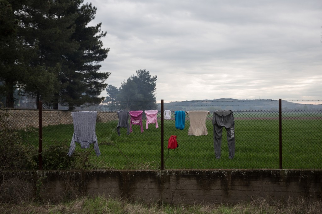 Migrants' clothes are hanging from a fence at the courtyard of an abandoned train workshop that is used by migrants as temporary shelter, near the village of Idomeni, Greece on March 12, 2016.